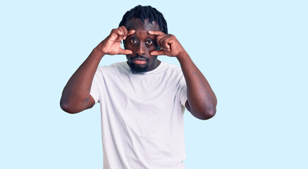 Young african american man with braids wearing casual white tshirt trying to open eyes with fingers, sleepy and tired for morning fatigue