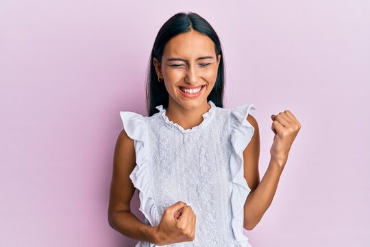 Young brunette woman wearing elegant summer shirt celebrating surprised and amazed for success with arms raised and eyes closed