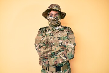 Young handsome man wearing camouflage army uniform and balaclava happy face smiling with crossed arms looking at the camera. positive person.