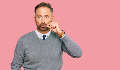 Handsome middle age man wearing business clothes mouth and lips shut as zip with fingers. secret...