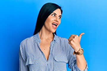 Fototapeta premium Young caucasian woman wearing casual clothes pointing thumb up to the side smiling happy with open mouth