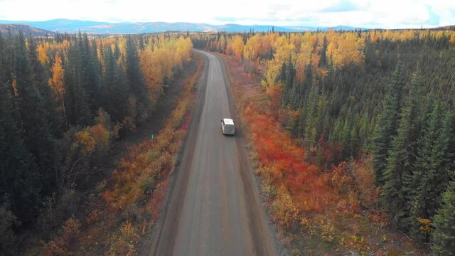 The Dempster Highway from North Klondike Hwy to northern Arctic Ocean in North West Territories driving through Yukon Territory in north Canada during fall, autumn gravel, isolated road drone, aerial 