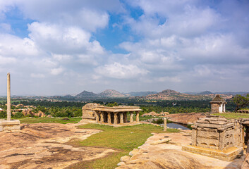 Fototapeta na wymiar Hampi, Karnataka, India - November 4, 2013: Sunset Hill AKA Hemakatu. Down hill are lots of temple ruins in front of rich agriculural land, rocky hills on horizon under blue cloudscape.