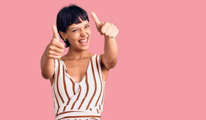 Young brunette woman with short hair wearing summer outfit approving doing positive gesture with hand, thumbs up smiling and happy for success. winner gesture.