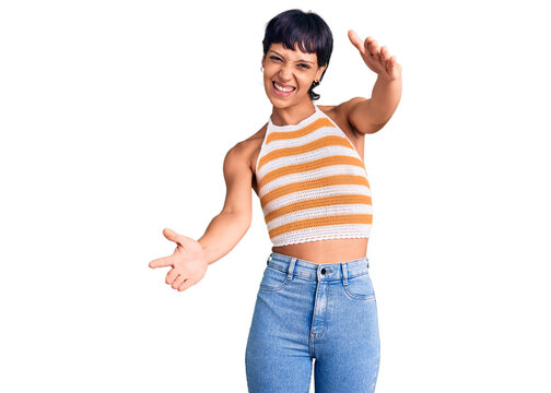 Young brunette woman with short hair wearing casual clothes looking at the camera smiling with open arms for hug. cheerful expression embracing happiness.