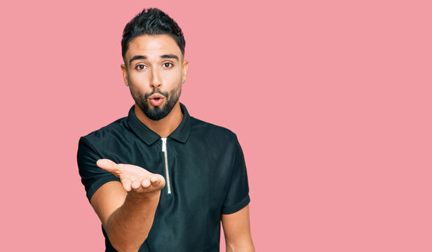 Young man with beard wearing sportswear looking at the camera blowing a kiss with hand on air being lovely and sexy. love expression.