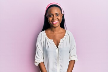 Young african woman wearing casual clothes over pink background looking positive and happy standing and smiling with a confident smile showing teeth