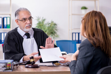 Old male judge and female client in the office