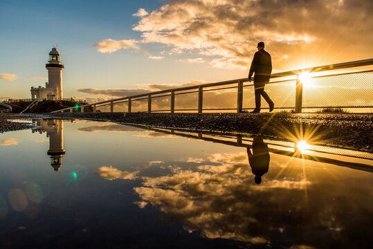 Man Walking By Railing Against Sky During Sunset