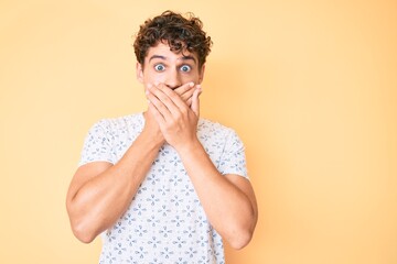 Young caucasian man with curly hair wearing casual clothes shocked covering mouth with hands for mistake. secret concept.