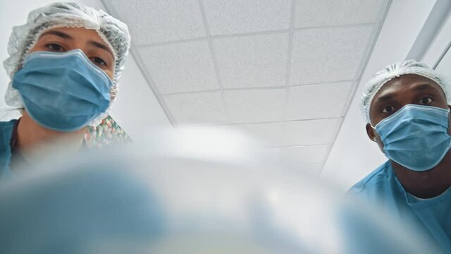POV shot of patient seeing several paramedic multi-race doctors running with stretcher bed to hospital operating room for surgery. Motion scene. Medical.