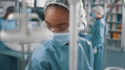 Afro-american professional young nurse or intern working in medical hospital office wearing eyewear and protective mask. Quarantine concept.