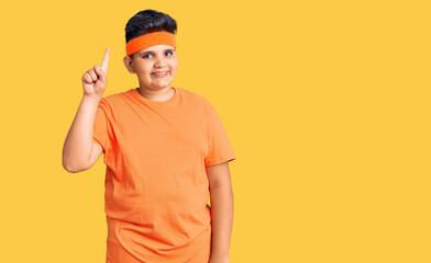 Little boy kid wearing sportswear showing and pointing up with finger number one while smiling confident and happy.