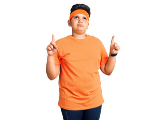 Little boy kid wearing sportswear pointing up looking sad and upset, indicating direction with fingers, unhappy and depressed.
