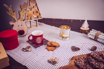 Fototapeta na wymiar table decorated with cinnamon and ginger cookies, Christmas lights, other Christmas items and a cup of hot coffee