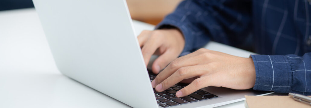 Employee Young Man Typing And Working On Laptop Computer On Desk At Home, Business Man Using Notebook And Check Email On Table, Hand Of Freelance Is Blogger, Lifestyle Concept, Banner Website.