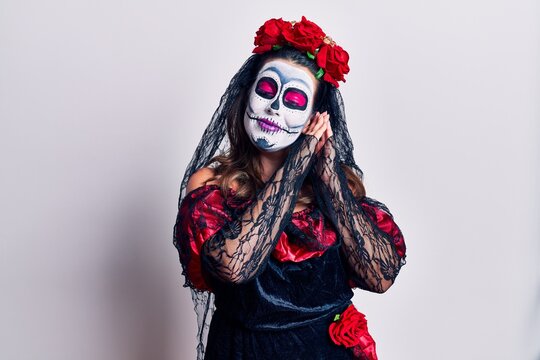 Young woman wearing day of the dead costume over white sleeping tired dreaming and posing with hands together while smiling with closed eyes.