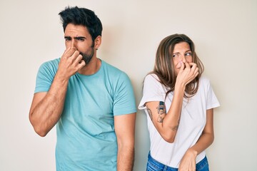 Beautiful young couple of boyfriend and girlfriend together smelling something stinky and...