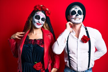 Couple wearing day of the dead costume over red suffering of neck ache injury, touching neck with hand, muscular pain