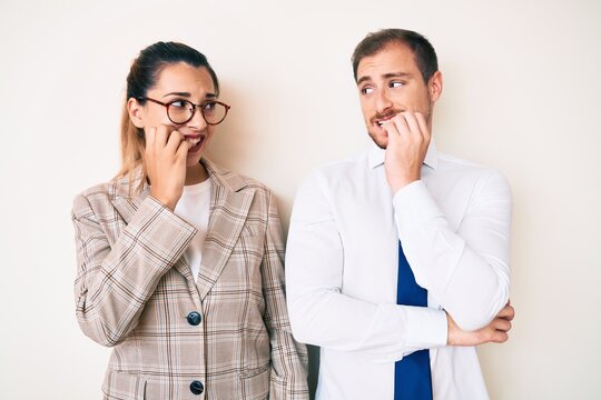 Beautiful couple wearing business clothes looking stressed and nervous with hands on mouth biting nails. anxiety problem.