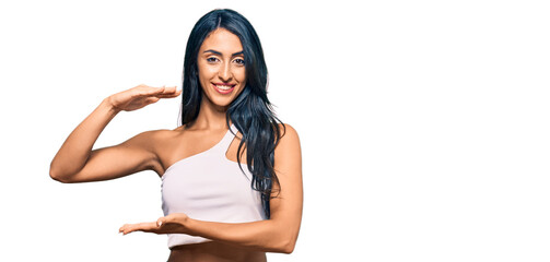 Beautiful hispanic woman wearing casual clothes gesturing with hands showing big and large size sign, measure symbol. smiling looking at the camera. measuring concept.