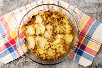 Close up on moussaka greek traditional meal with potatoes and meat in the glass pot on marble table with copy space