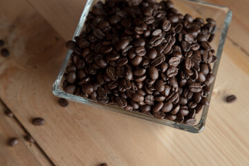Café negro en grano sobre madera y en un recipiente de cristal. Granos de café de chiapas
 