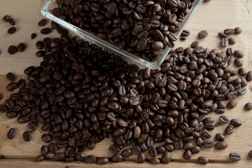 Café negro en grano sobre madera y en un recipiente de cristal 