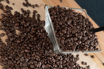 Café negro en grano sobre madera y en un recipiente de cristal 