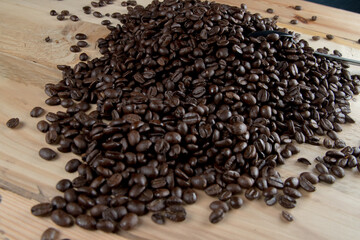 Café negro en grano sobre madera y en un recipiente de cristal 
