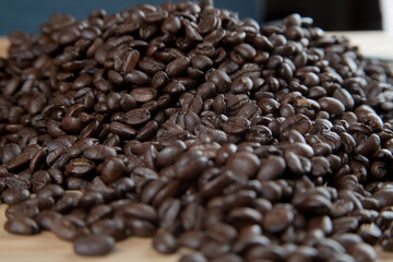 Café negro en grano sobre madera y en un recipiente de cristal 