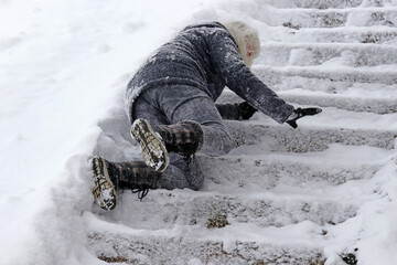 Eine Frau ist auf der schneebedeckten Treppe ausgerutscht und hingefallen