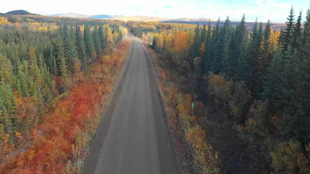 The Dempster Highway from North Klondike Hwy to northern Arctic Ocean in North West Territories driving through Yukon Territory in north Canada during fall, autumn gravel, isolated road drone, aerial 