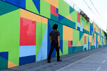 man walking on the street in front of colorful wall
