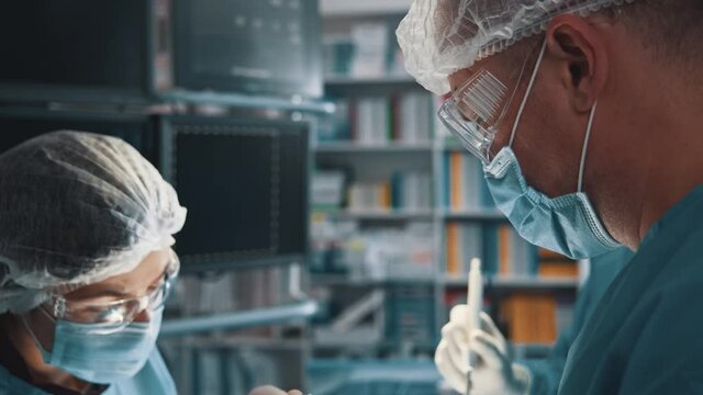 Professional skillful surgeon with younger nurse perfom surgical procedure in operating room. Medical staff concept. Healthcare. Quarantine.