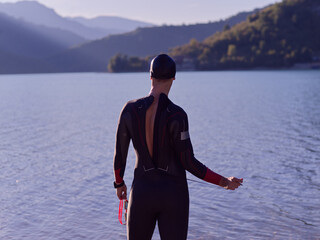 authentic triathlon athlete getting ready for swimming training on lake