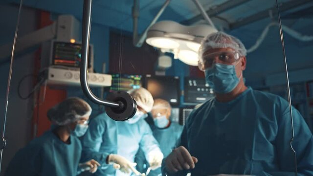 Portrait of professional male surgeon interacting futuristic medical app virtual touchscreen holographic glass panel glass at modern high tech hospital. Surgery. Future.