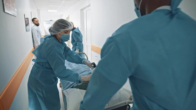 Group of diverse paramedic doctors hurrying in hospital corridor to operating room to save patient. Surgery concept. Healthcare, assistance.