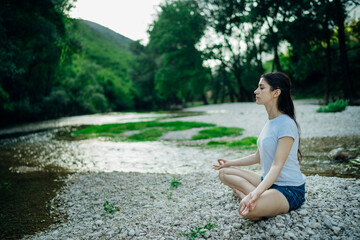 Meditation yoga woman siting at Lotus position on the shore of river.Serenity and yoga practice.Healthy lifestyle.Self isolation in nature.Lockdown beach trip.Mindfulness.Breathing exercise