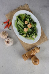 Stir fried mustard greens or cah sawi. Traditional asian indonesian food, cooked veggies, spicy vegetable dish serve on white plate