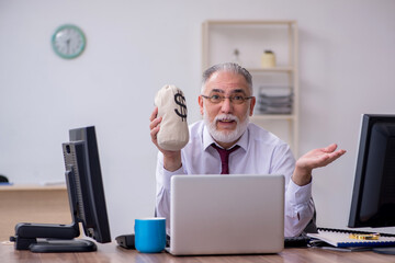 Old male boss sitting at desktop in the office