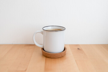 Fototapeta na wymiar White hot coffee cup on wooden table and white wall with copy space.