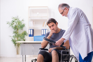 Young male patient in wheel-chair visiting old doctor radiologis