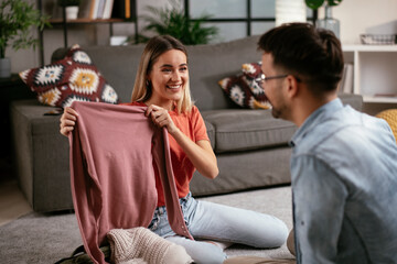 Loving couple packing clothes into travel bag. Boyfriend and girlfriend preparing for the trip..