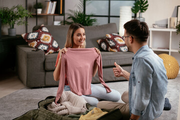 Obraz premium Loving couple packing clothes into travel bag. Boyfriend and girlfriend preparing for the trip..