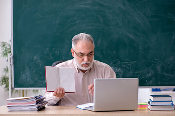 Old male teacher sitting in the classroom