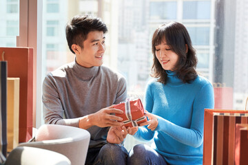 young asian man giving girlfriend a christmas gift or a birthday present