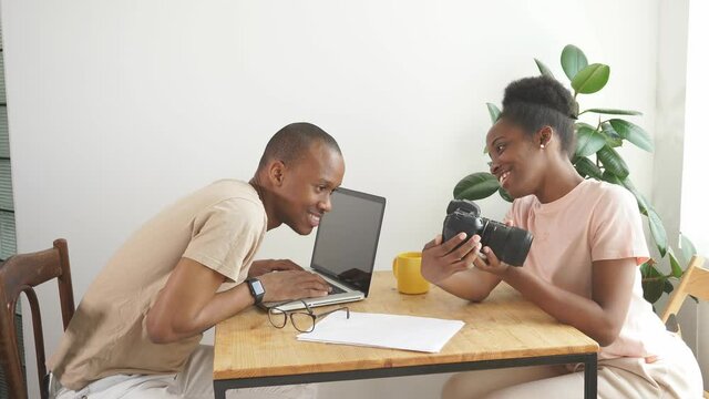 Cheerful woman shows photo on camera to her husband, they have conversation and discuss. at home