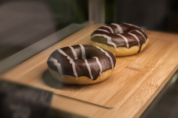 Two chocolate doughnuts in the refrigerator window in a coffee shop close-up