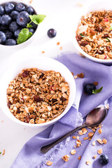Muesli with blueberris in a bowl   on white wooden background. Delicious and healthy breakfast.